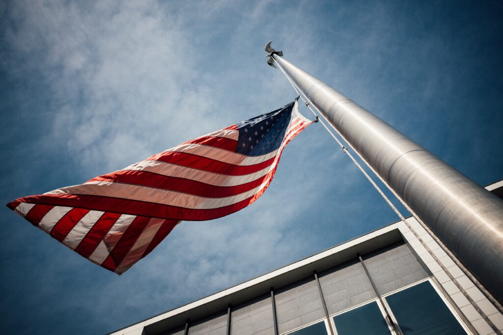 American flag at half mast in front of a building, viewed from below