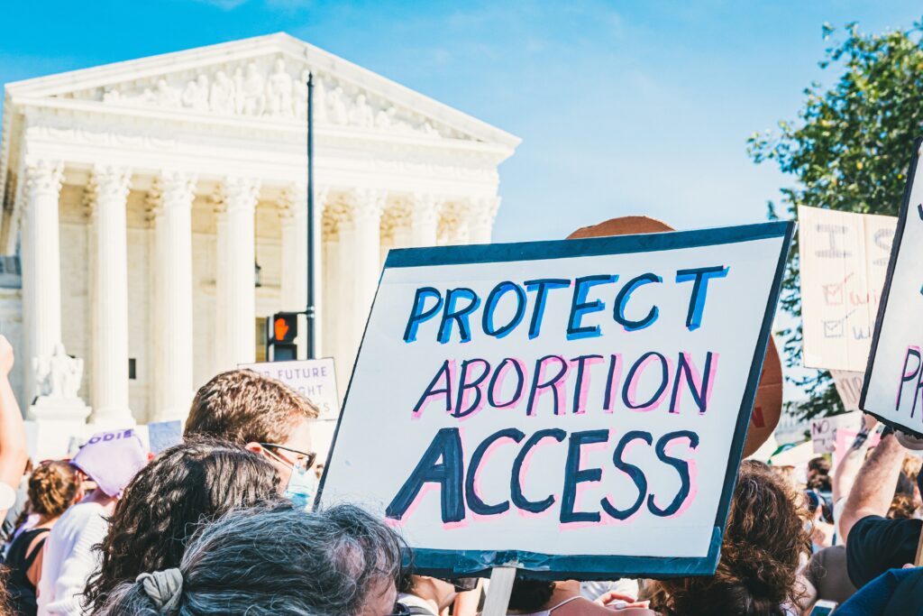A group of protestors in front of the Supreme Court. One is holding a sign saying "Protect abortion access."